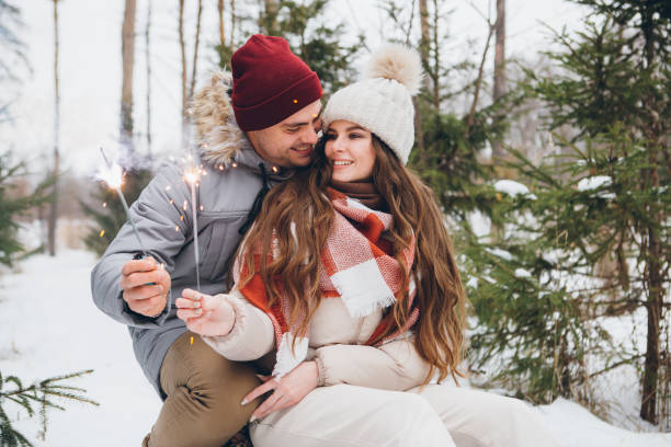 istock Couple hugs and burns sparklers in a winter coniferous forest while sitting on a sled 1366809339