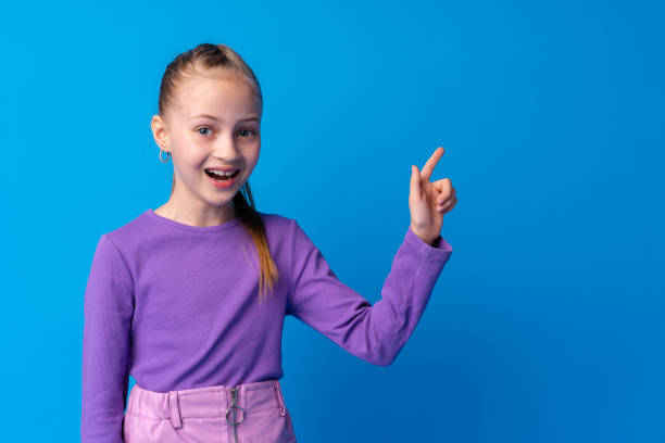 istock Little girl pointing at copy space against blue background 1366810913