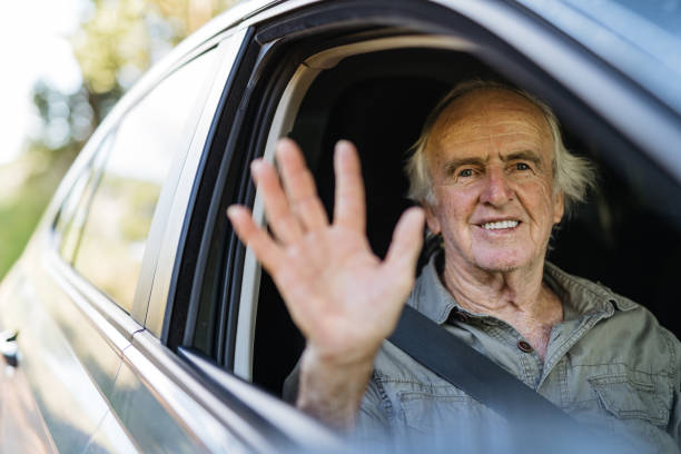 istock Senior man waving from car window 1366811091