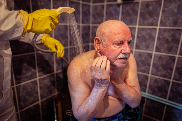 Caucasian senior male patient washing his face during assisted bath stock photo