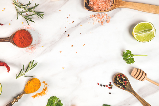 Kitchen table with spices and dry herbs on white marble background
