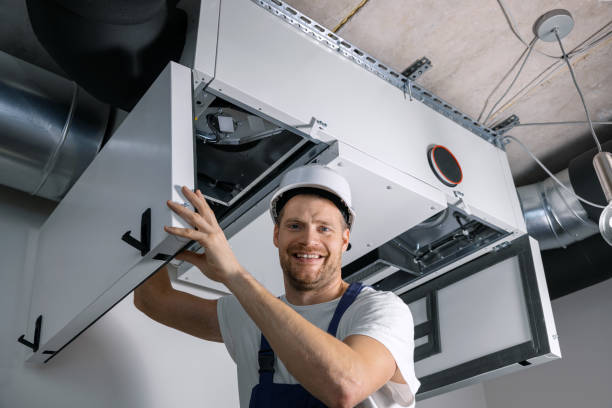 smiling hvac technician at work. ventilation, heating system maintenance and repair stock photo