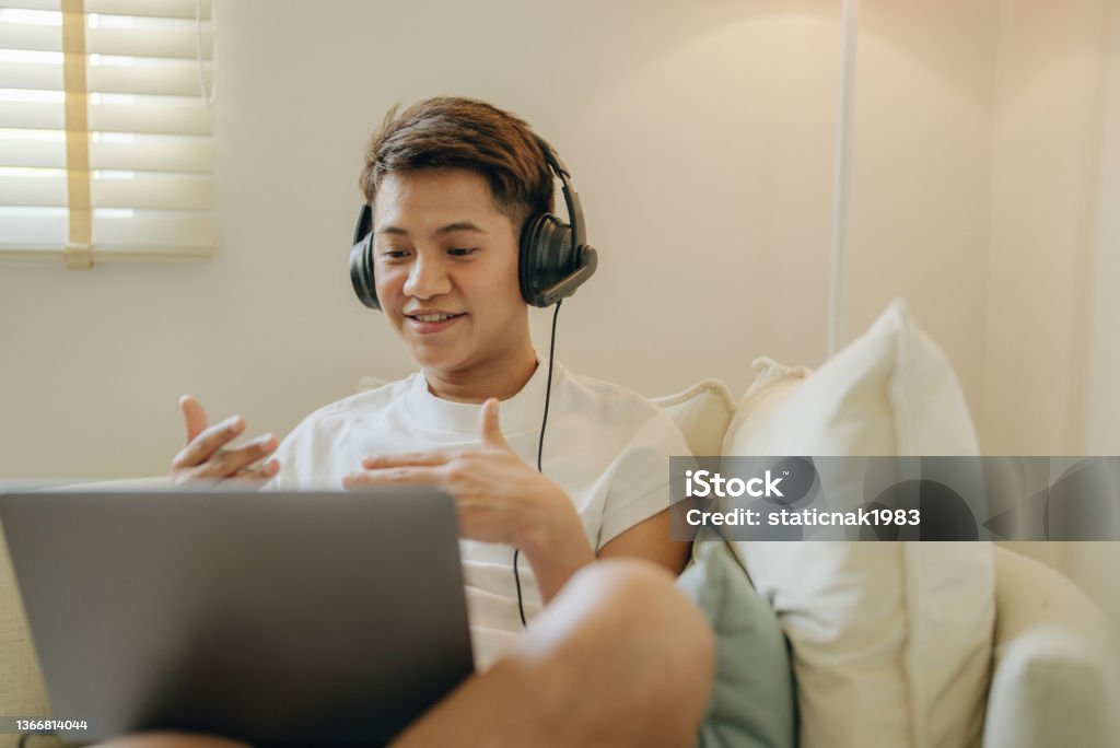 New Normal : Work From Home. Gay person having video teleconference on her laptop at home, online learning or working from home. Non-Binary Gender Stock Photo