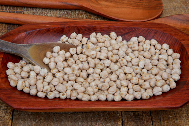 Chickpea portion on red wood platter Chickpea portion on red wood platter on rustic wooden table Gram of Carbohydrates stock pictures, royalty-free photos & images