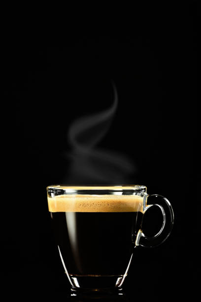 Espresso on a dark background, the steam rises above the coffee. Coffee for breakfast in an Italian cafe shop, vertical shot, selective focus stock photo