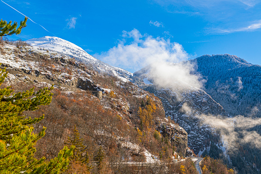 Alpe-d'Huez famous road with impossible turns, during autumn, with first snow in the mountain peaks.