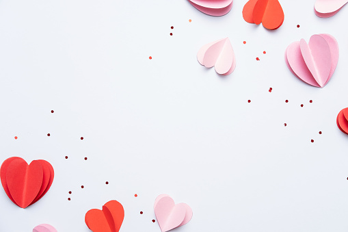 Elementos de papel en forma de corazones sobre fondo blanco. Símbolos de amor para Mujeres Felices, Madre, Día de San Valentín, cumpleaños. Vista superior de la tarjeta de felicitación. Tendido plano photo