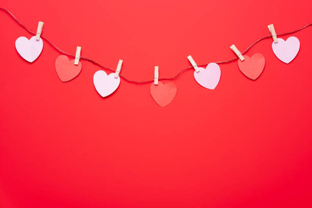 istock Red hearts garland hanging on red wall background 1366821162