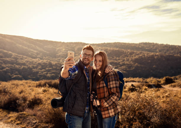 istock Couple with backpacks making selfie while they hiking on the mountain. 1366822310