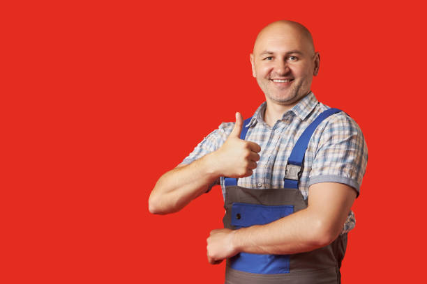 istock Bald, unshaven man in work clothes shows an ok hand gesture on a red background 1366823549
