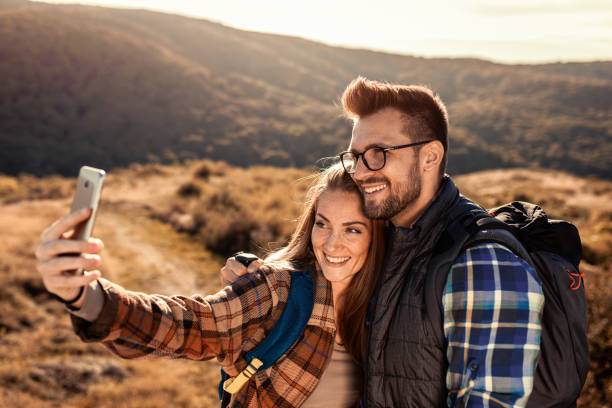 istock Couple with backpacks making selfie while they hiking on the mountain. 1366823745