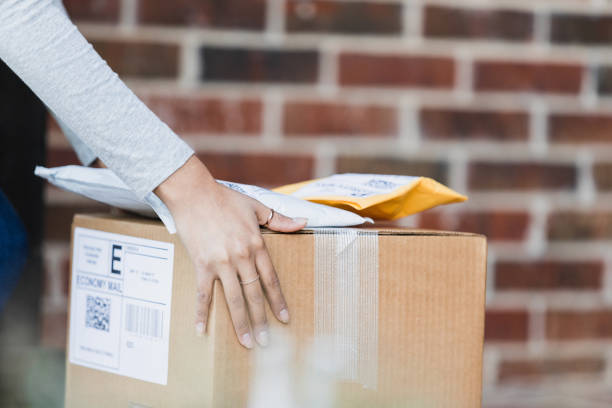 A close up photo of an unrecognizable woman's hands picking up or dropping off packages.