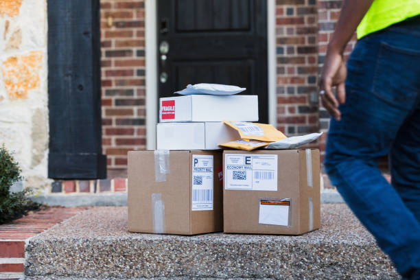 Unrecognizable delivery man approaches stack of mail for pick-up