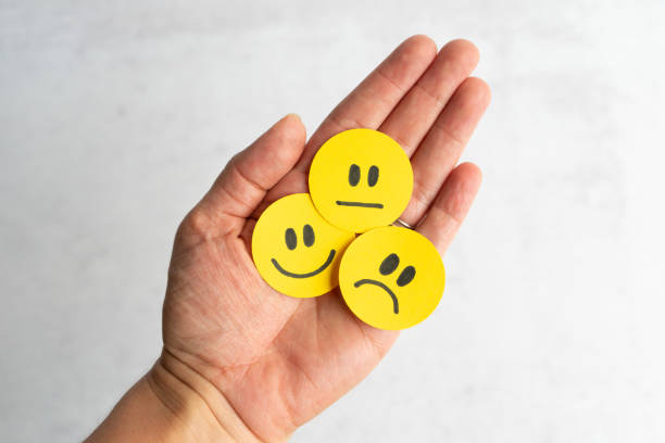 Emotional Intelligence Woman’s hand holding yellow emotional faces emotional series stock pictures, royalty-free photos & images