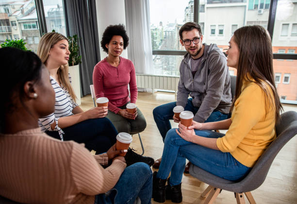 istock Diverse group of people sitting in circle in group therapy session. 1366830785
