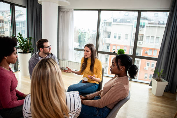 istock Diverse group of people sitting in circle in group therapy session. 1366831705