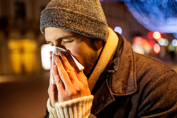 istock Young man with Cold or Flu is Blowing his Nose on a street 1366834163