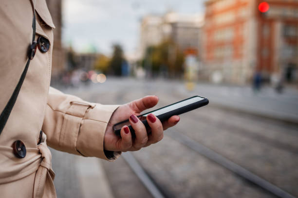 istock Woman checking her smart phone while waiting at bus stop in city 1366834431