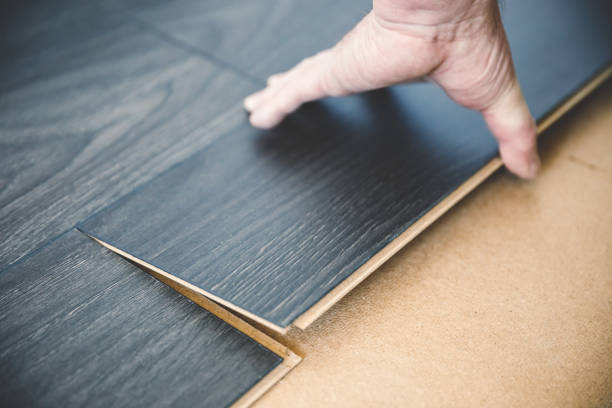 Installing a new dark wood laminate flooring with fiber insulation below stock photo