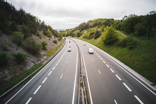 Color photography of A40 highway, viewed from high angle view with car traffic, in middle of french countryside in Alps in summer. Taken in Bugey mountains, in Ain, Auvergne-Rhone-Alpes region in France.