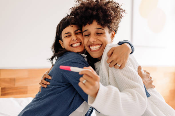 Celebrating having a baby on the way Celebrating having a baby on the way. Excited young lesbian couple smiling cheerfully and embracing each other after taking a home pregnancy test. Young female couple expecting a baby. family planning stock pictures, royalty-free photos & images