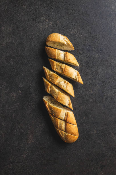 istock Roasted baguette with garlic butter. Crunchy sliced garlic bread on black table. 1366841825
