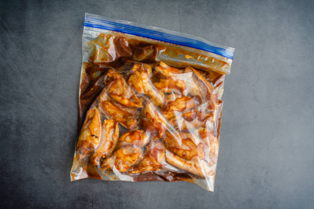 Raw Chicken Wings Marinating in a Plastic Bag Uncooked chicken wings and marinade in a ziplock bag marinade stock pictures, royalty-free photos & images
