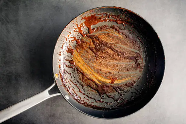 An unwashed frying pan covered in a sticky glaze