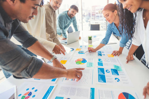 Multi racial group of people working with Paperwork on a board room table at a business presentation or seminar