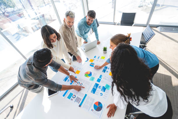 istock Multi racial group of people working with Paperwork on a board room table at a business presentation or seminar. 1366844848