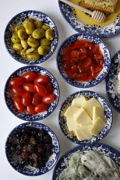 Istanbul, Turkey-January 23, 2022: Traditional spread Turkish breakfast on white table. Various breakfast food products on ceramic plates with blue navy floral pattern. Grilled green and black olives, quince jam, moldy Kars tuluk cheese, Kars cheddar and cherry tomatoes. Shot with Canon EOS R5.