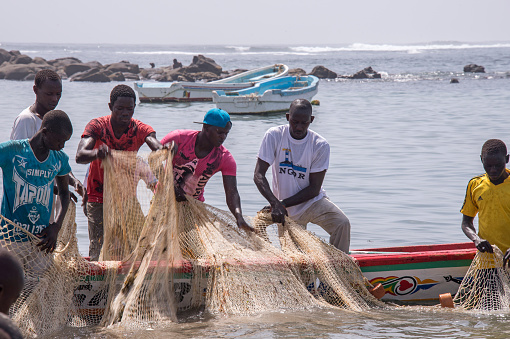 Senegal, West Africa - June 01, 2014: Group of fishermen collecting nets on the beach of Ngor, on the coast of Dakar