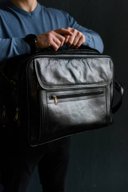 istock Man holding black leather travel bag. Soft light 1366854554