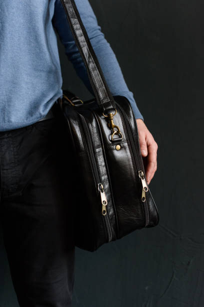 istock Man holding black leather travel bag. Soft light 1366854671