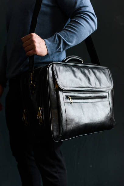 istock Man holding black leather travel bag. Soft light 1366855292