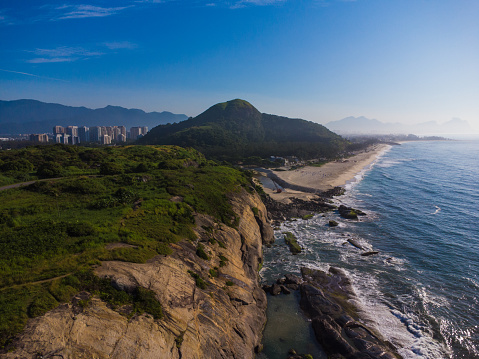 Vista aérea de Praia do Secreto cerca de la playa de Prainha, en Río de Janeiro, Brasil. Grandes colinas alrededor. Día soleado al amanecer. Recreio dos Bandeirantes al fondo. Foto de drone photo
