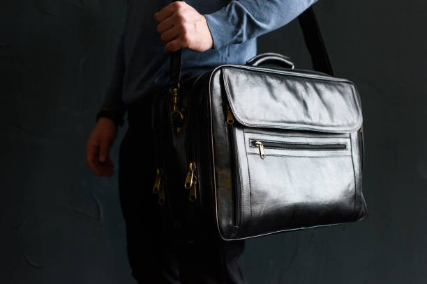 istock Man holding black leather travel bag. Soft light 1366855417