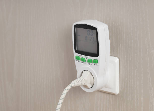 istock Wattmeter for measuring electricity costs with plug connected to the outlet, in socket on wall 1366859323