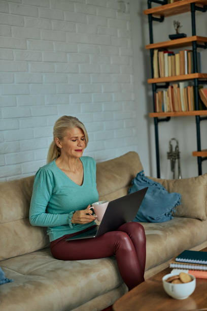 istock Woman relaxing on couch and using laptop 1366861620