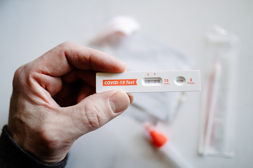 A persons hands taking a COVID-19 / Coronavirus home testing kit, meant to speed up results and prevent exposure and spread among infected individuals.