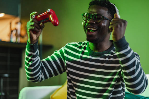 A young African-American man is at home on the couch, he is having fun playing video games