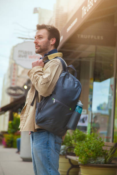istock Man wears gray backpack on city street 1366870130