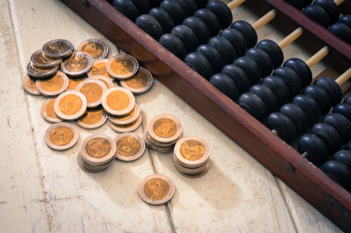 Golden coins with antique abacus on table.