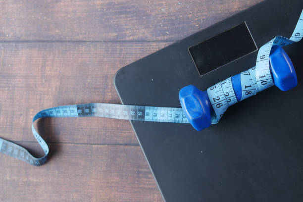 istock Fitness concept with dumbbell and weight scale on black 1366888216