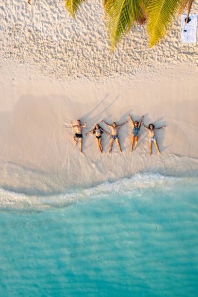 luftaufnahme von freunden, die am strand liegen - women cheerful vertical 20s stock-fotos und bilder