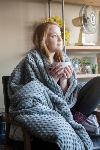 istock Young redhead woman using soft weighted blanket in her modern apartment 1366896041