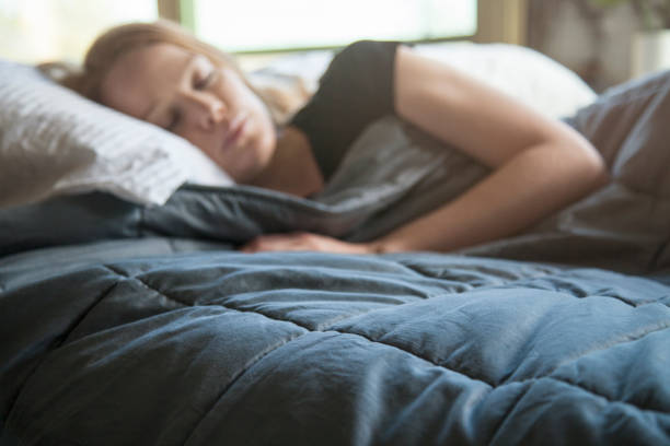 Young redhead woman using soft weighted blanket in her modern apartment stock photo