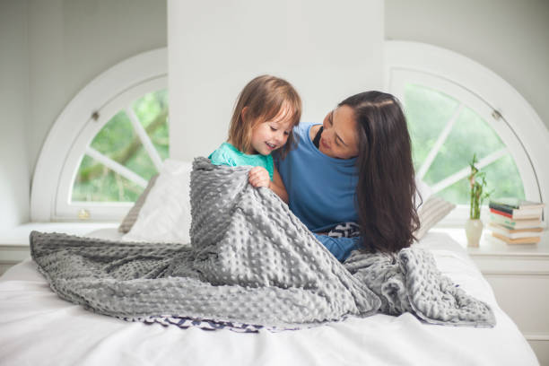 Mother and daughter on bed with blanket stock photo
