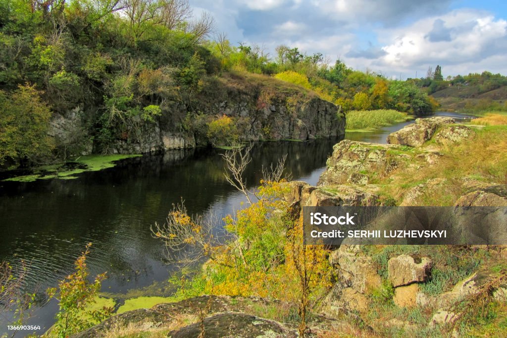 Vertical stone rocks on the bank of the river. Vertical stone rocks on the bank of the river. A picturesque view of the Tyasminsky canyon with river on sunny day. Kam'yanka Cherkasy region, Ukraine. Absence Stock Photo