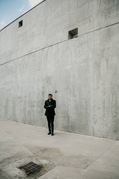 istock Man in black agaisnt the gray wall 1366905573